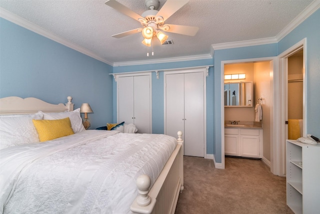 bedroom with ensuite bath, ornamental molding, ceiling fan, light carpet, and a textured ceiling