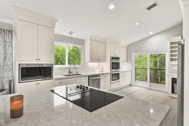 kitchen featuring sink, tasteful backsplash, pendant lighting, stainless steel appliances, and white cabinets