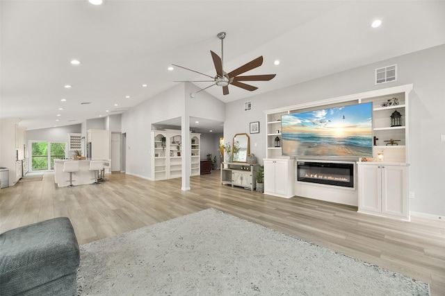 unfurnished living room featuring built in shelves, ceiling fan, vaulted ceiling, and light wood-type flooring