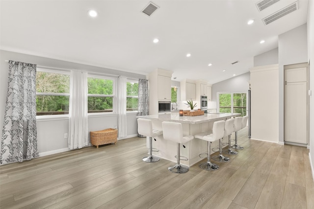 kitchen with white cabinetry, a kitchen bar, light hardwood / wood-style floors, and a kitchen island