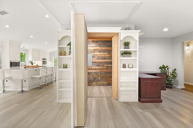 bar featuring appliances with stainless steel finishes, sink, white cabinets, and light hardwood / wood-style floors