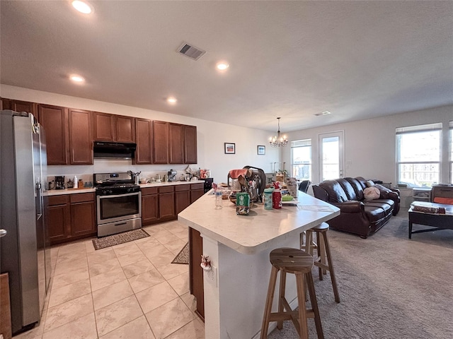 kitchen with a kitchen island, pendant lighting, a kitchen breakfast bar, stainless steel appliances, and an inviting chandelier