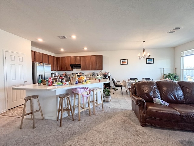 kitchen featuring a breakfast bar area, a chandelier, a center island, hanging light fixtures, and stainless steel fridge with ice dispenser