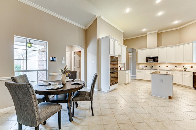 dining room with light tile patterned floors, a towering ceiling, and ornamental molding