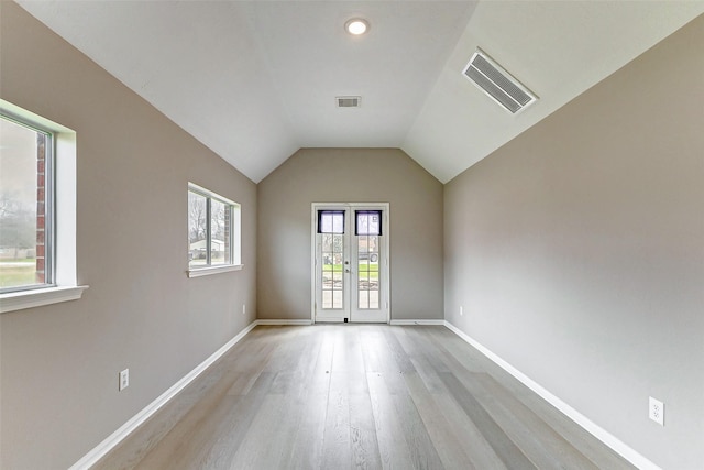 spare room featuring lofted ceiling, light hardwood / wood-style floors, and french doors