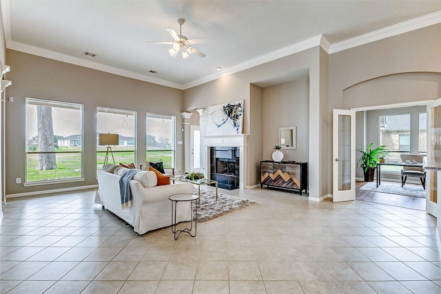 living room with ceiling fan, ornamental molding, a high ceiling, and light tile patterned floors