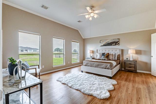 bedroom with ceiling fan, lofted ceiling, ornamental molding, and light wood-type flooring