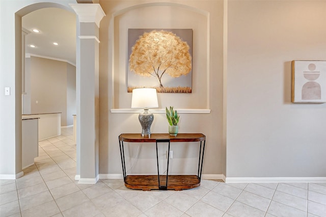 corridor with ornate columns, light tile patterned flooring, and crown molding