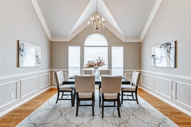 dining room with an inviting chandelier, vaulted ceiling, light hardwood / wood-style floors, and crown molding