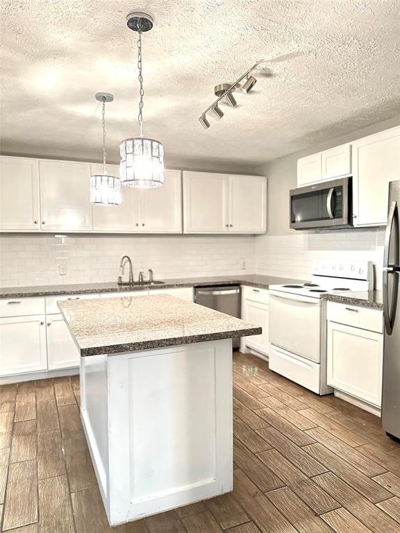 kitchen with decorative backsplash, appliances with stainless steel finishes, white cabinets, and decorative light fixtures