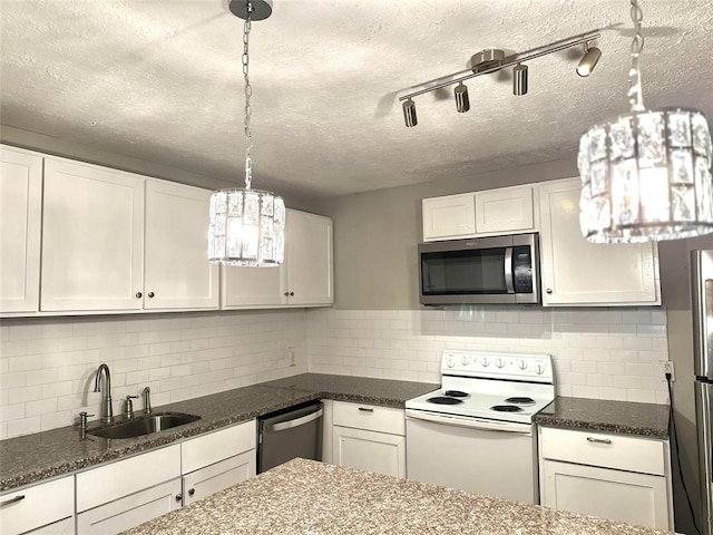 kitchen featuring pendant lighting, sink, appliances with stainless steel finishes, white cabinetry, and dark stone counters