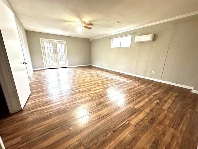 empty room featuring a wealth of natural light, an AC wall unit, hardwood / wood-style floors, and french doors