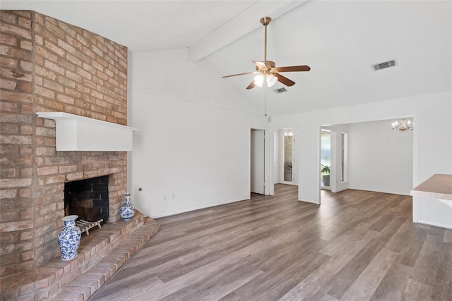 unfurnished living room featuring ceiling fan with notable chandelier, hardwood / wood-style floors, high vaulted ceiling, beamed ceiling, and a brick fireplace