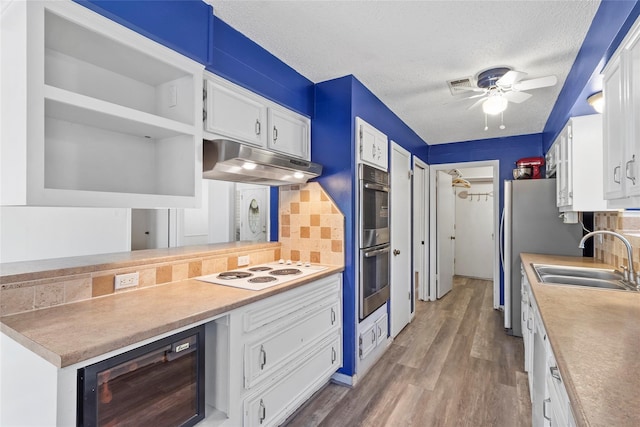 kitchen with sink, white cabinetry, a textured ceiling, appliances with stainless steel finishes, and decorative backsplash