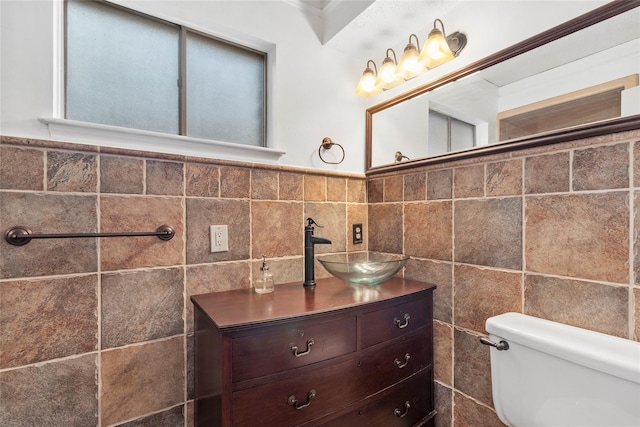 bathroom with vanity, toilet, and tile walls