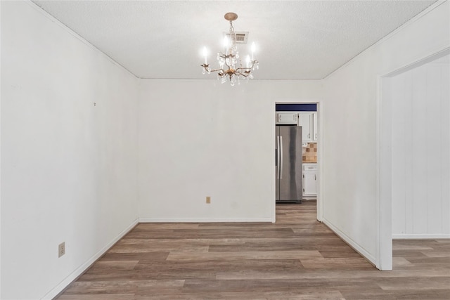 spare room with hardwood / wood-style flooring, a notable chandelier, and a textured ceiling