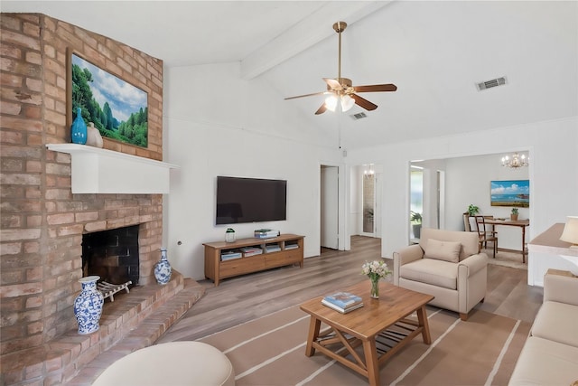 living room with high vaulted ceiling, a brick fireplace, hardwood / wood-style floors, beamed ceiling, and ceiling fan with notable chandelier