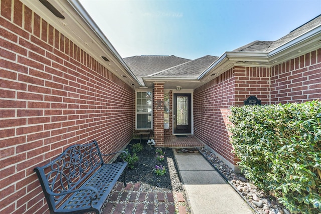 property entrance featuring brick siding and roof with shingles