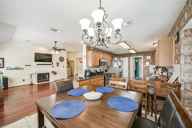 dining space with lofted ceiling, visible vents, a fireplace, and ceiling fan