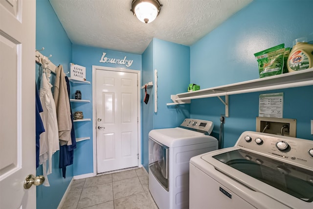 clothes washing area featuring laundry area, light tile patterned floors, baseboards, washing machine and clothes dryer, and a textured ceiling