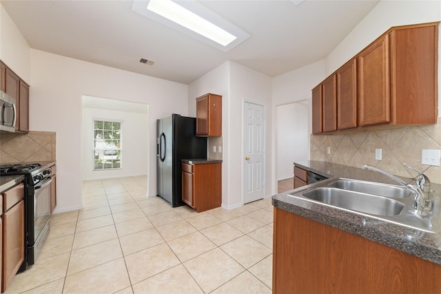 kitchen with tasteful backsplash, light tile patterned floors, sink, and black appliances