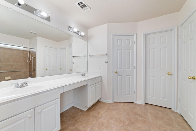 bathroom with tile patterned flooring, vanity, and walk in shower