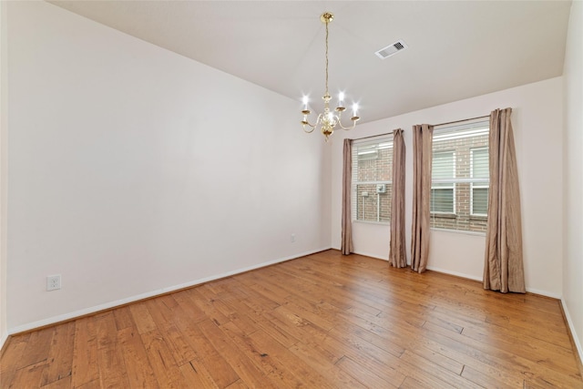 unfurnished room featuring an inviting chandelier and light hardwood / wood-style flooring