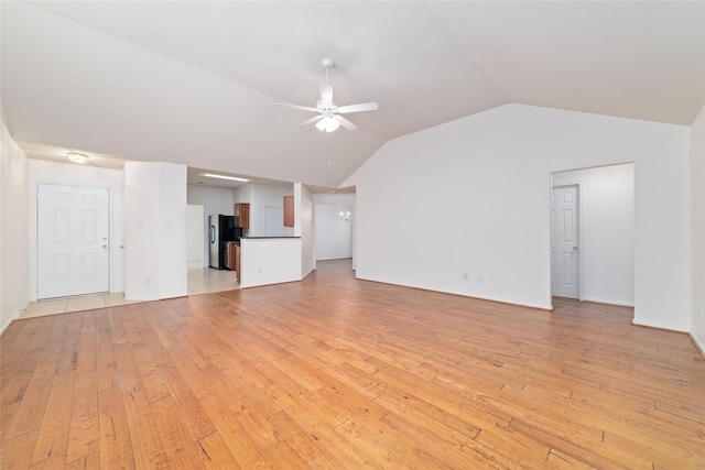 unfurnished living room featuring lofted ceiling, ceiling fan with notable chandelier, and light hardwood / wood-style flooring