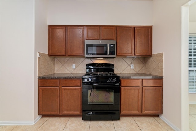 kitchen featuring tasteful backsplash, light tile patterned flooring, and black gas range