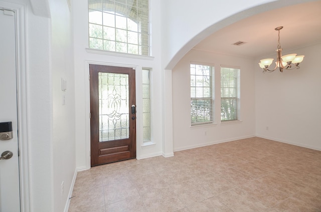 tiled entrance foyer featuring ornamental molding and a notable chandelier