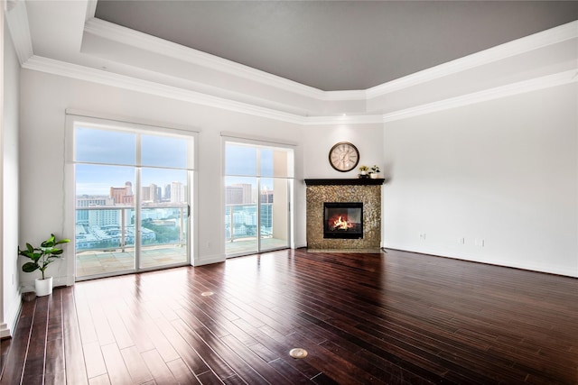 unfurnished living room featuring a city view, a raised ceiling, a glass covered fireplace, and dark wood-style floors