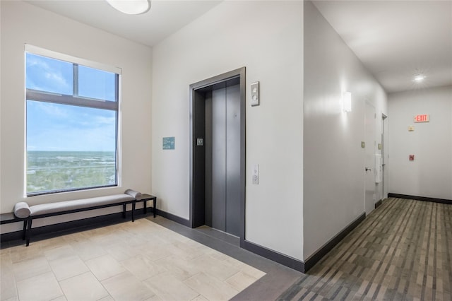 hallway with baseboards and elevator