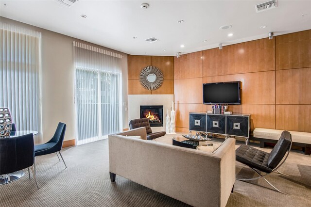 carpeted living room with a glass covered fireplace, baseboards, recessed lighting, and visible vents