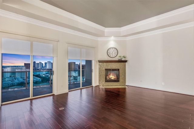 unfurnished living room with dark wood-type flooring, a city view, a fireplace, and ornamental molding