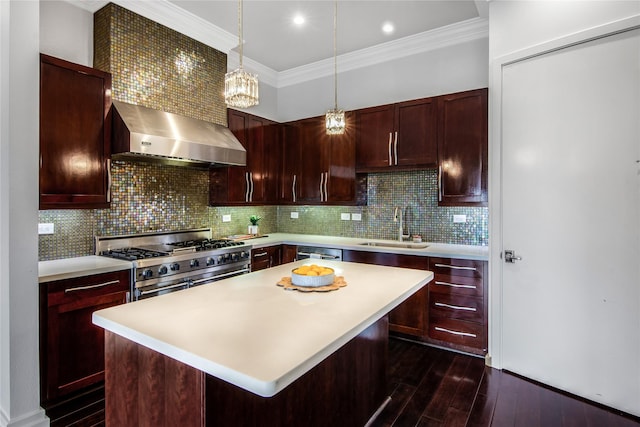 kitchen with ornamental molding, wall chimney range hood, light countertops, a sink, and appliances with stainless steel finishes