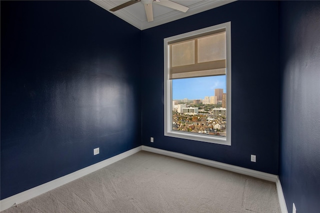 carpeted empty room featuring baseboards, ornamental molding, and a ceiling fan