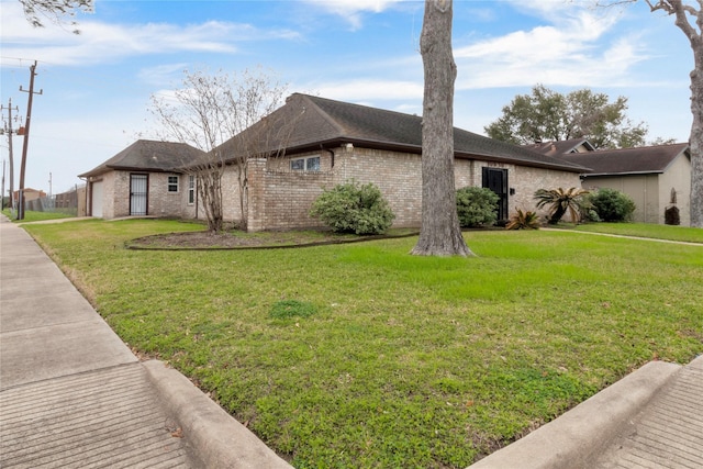 view of front of property with brick siding, a front lawn, and an attached garage