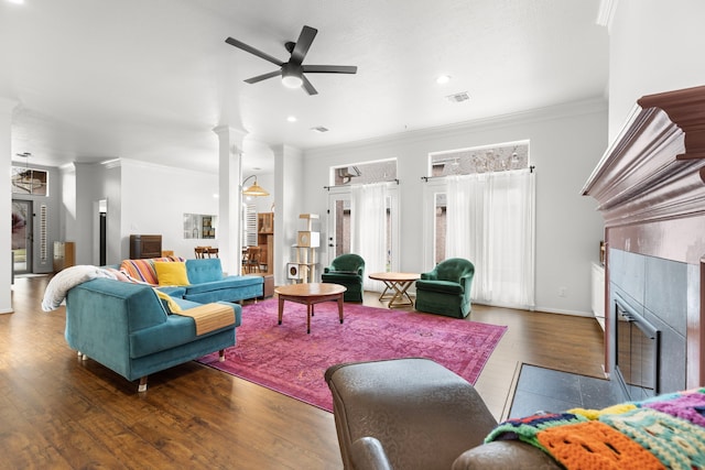 living room with ornate columns, a fireplace, dark hardwood / wood-style flooring, ceiling fan, and crown molding