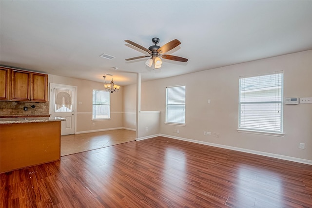 unfurnished living room with dark wood-type flooring and ceiling fan with notable chandelier