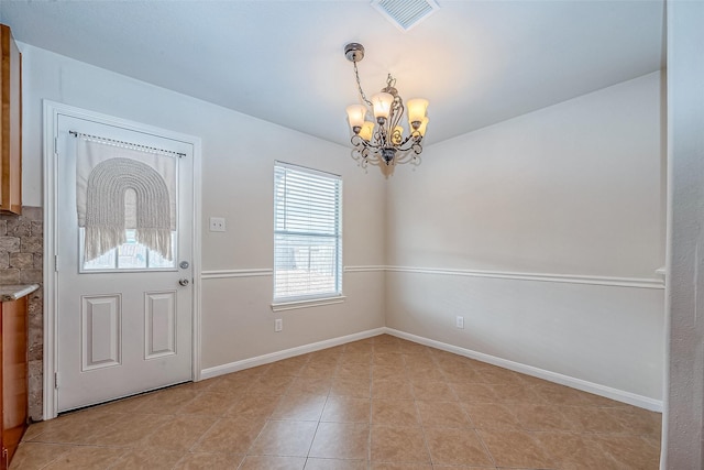 entryway with light tile patterned floors and an inviting chandelier