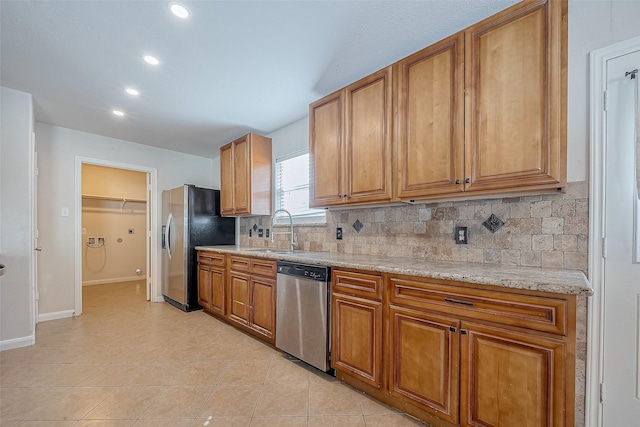 kitchen with sink, light stone counters, light tile patterned floors, stainless steel appliances, and backsplash