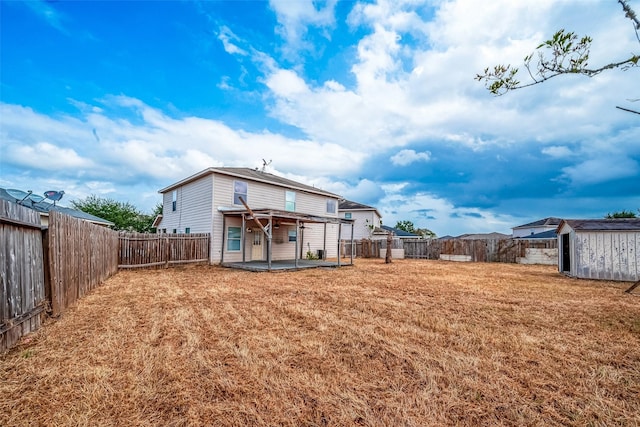 rear view of property featuring a yard, a patio, and a storage unit