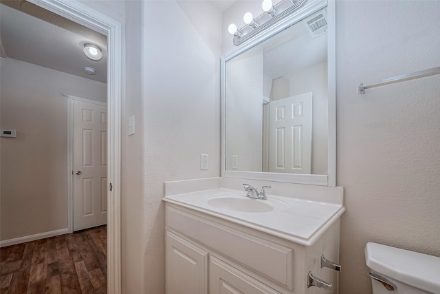 bathroom featuring wood-type flooring, vanity, and toilet