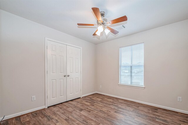 unfurnished bedroom featuring hardwood / wood-style flooring, ceiling fan, and a closet