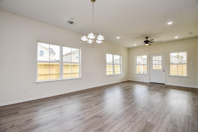 empty room with dark wood-type flooring and ceiling fan with notable chandelier