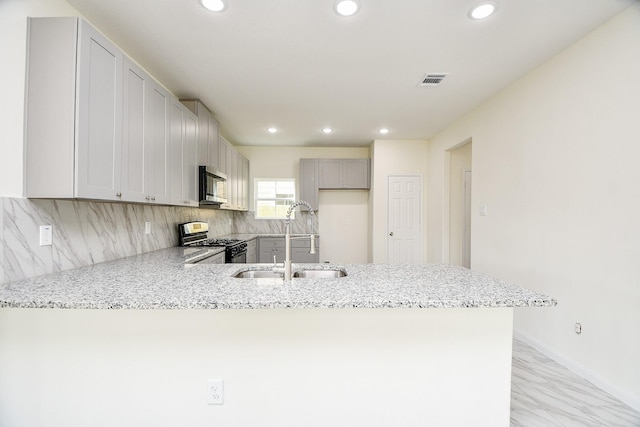 kitchen featuring sink, appliances with stainless steel finishes, gray cabinetry, backsplash, and kitchen peninsula