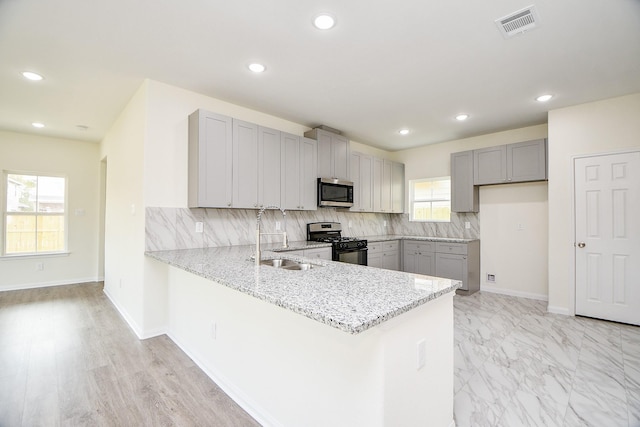 kitchen with sink, gray cabinets, kitchen peninsula, stainless steel appliances, and decorative backsplash