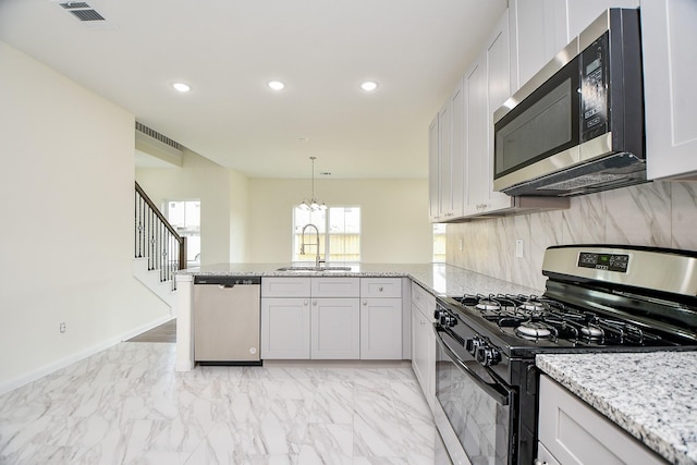 kitchen with sink, appliances with stainless steel finishes, white cabinets, decorative light fixtures, and kitchen peninsula