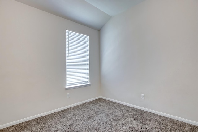 empty room with vaulted ceiling and carpet flooring