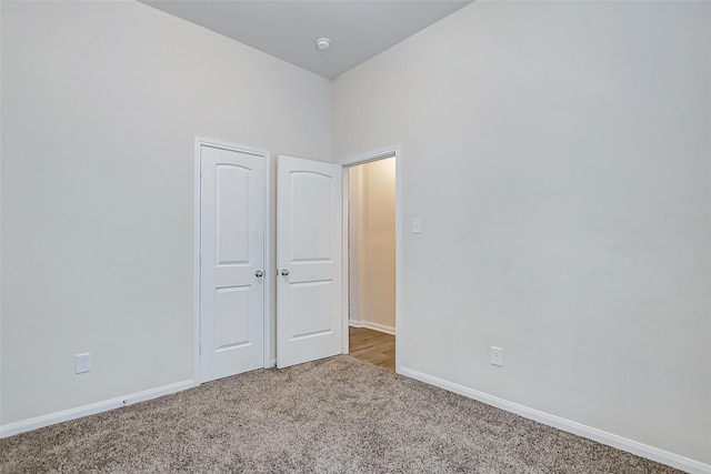 unfurnished bedroom with carpet flooring and vaulted ceiling